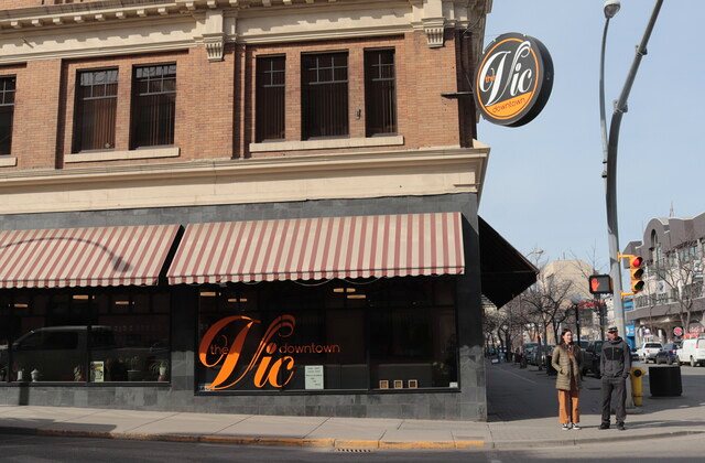 The Vic Downtown storefront on the corner of 4th and Victoria, with its round illuminated sign and striped awning