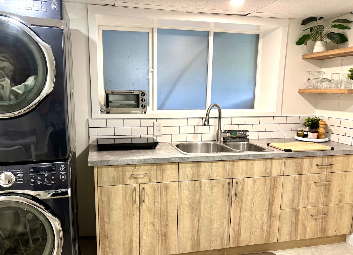 Compact kitchenette with sink, toaster oven, shelves, and in-suite laundry