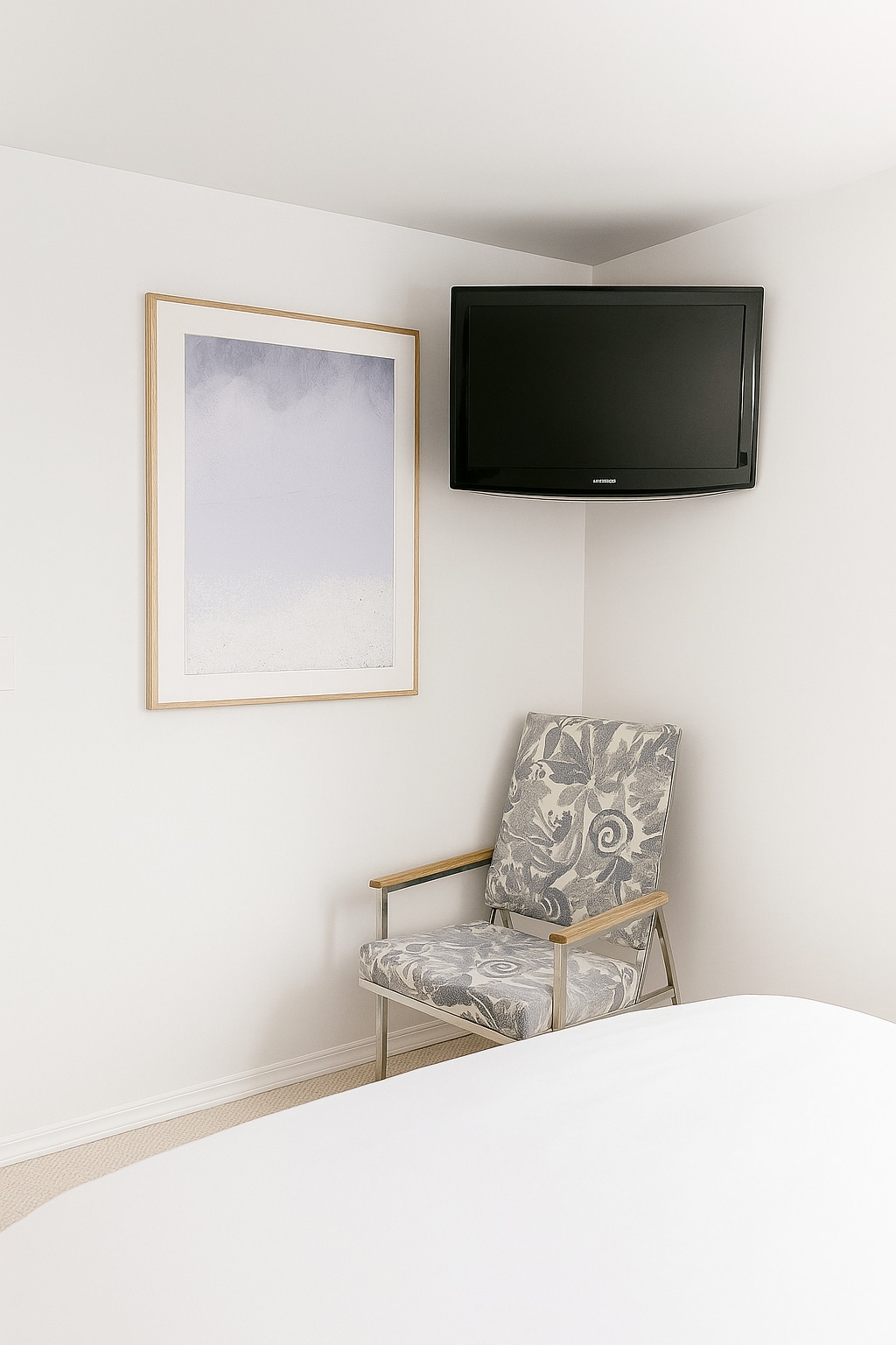 Bright sleeping area with wall-mounted streaming TV and reading chair